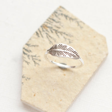The stamped silver feather stacking ring is styled on an organic stone