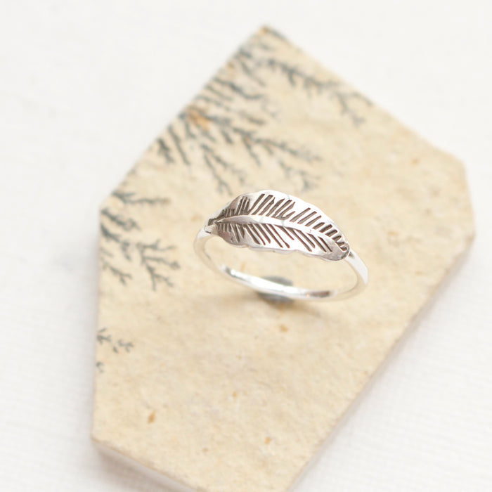 The stamped silver feather stacking ring is styled on an organic stone