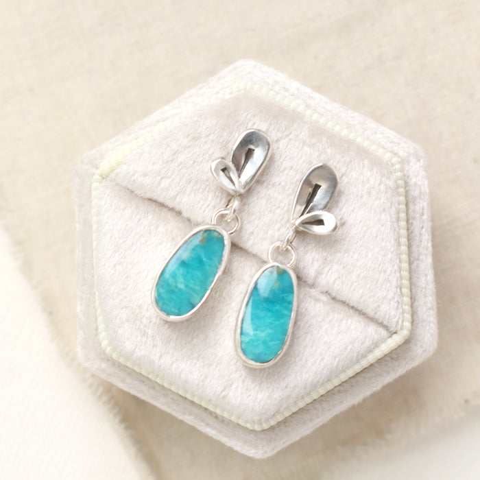 The feminine turquoise petal post earrings styled on a velvet box