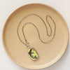 The fish tales vintage plate necklace styled on a tan plate to show the unique hook toggle closure