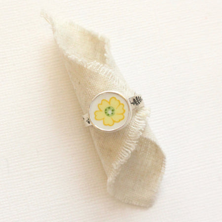 The flower vintage plate ring styled on rolled tan linen