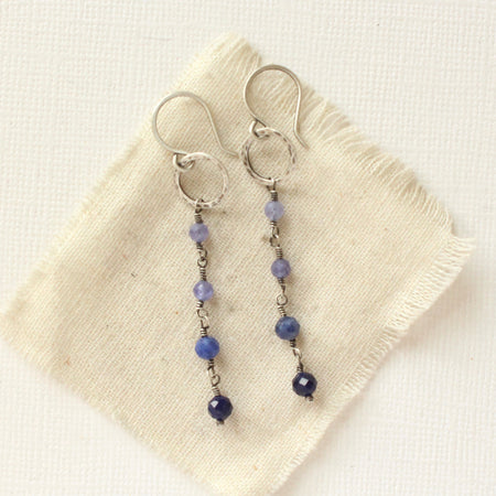 The flowing vinca mini hoop earrings styled on tan linen