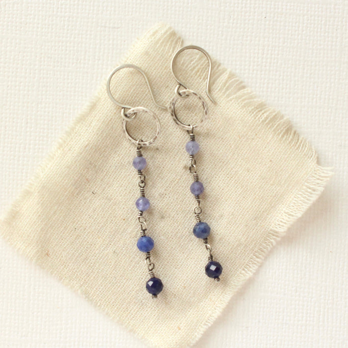 The flowing vinca mini hoop earrings styled on tan linen