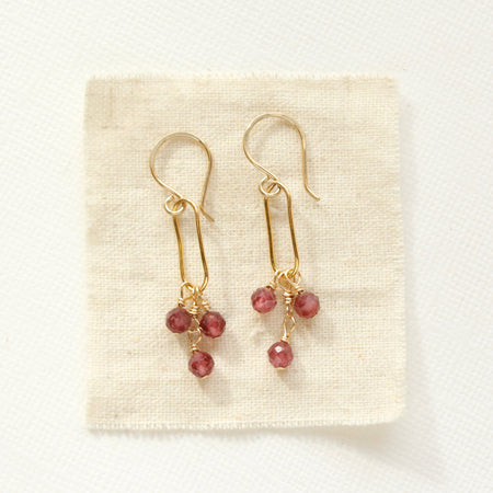 The garnet trio gold hoop earrings styled on tan linen
