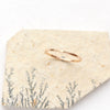 The hammered gold stacking ring styled on a tan rock