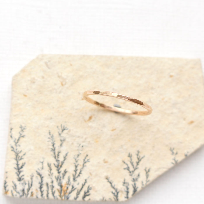 The hammered gold stacking ring styled on a tan rock