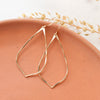 The gold fill pointed hoop earrings styled on an orange plate with dried grass