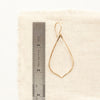 A gold fill pointed teardrop hoop earring next to a ruler for size reference