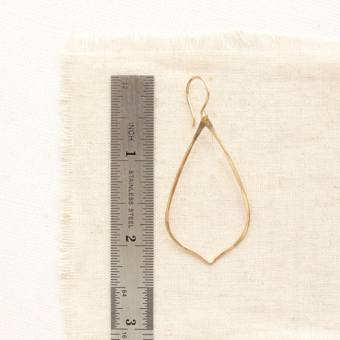 A gold fill pointed teardrop hoop earring next to a ruler for size reference