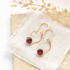 The garnet delhi earrings styled on a tan rock with linen and dried grass