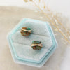 The gold wrapped turquoise square post earrings styled on a blue velvet box with dried grass