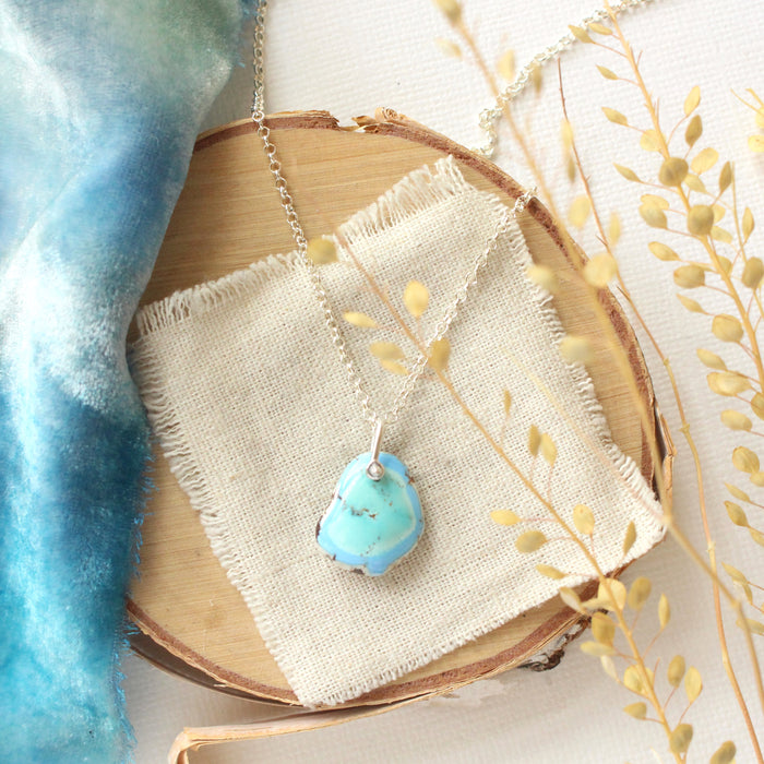The gold hills turquoise necklace styled on wood with blue velvet and dried grass