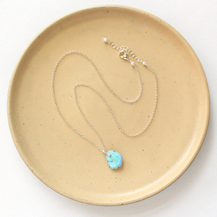 The golden hills turquoise necklace styled on a tan plate to show the adjustable lobster clasp closure