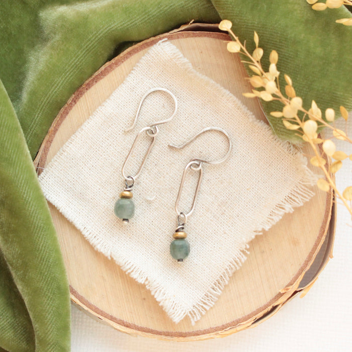 The green apatite hoop earrings styled on wood with green velvet and dried grass