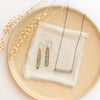 The green apatite bronze bar necklace styled on a tan plate with the matching earrings 