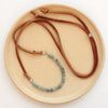 The apatite adjustable leather necklace styled on a tan plate to show the entire piece
