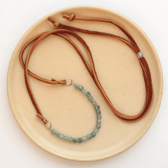 The apatite adjustable leather necklace styled on a tan plate to show the entire piece