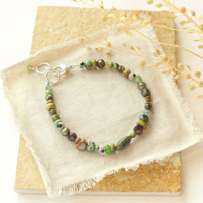 The green eyes gemstone bracelet styled on a tan rock with dried grass