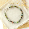 The green eyes gemstone bracelet styled on a tan rock with linen and dried grass