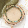 The lana bracelet styled on wood with green velvet, linen, and dried grass