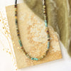 The beaded lana necklace styled on a tan rock with green velvet and dried grass