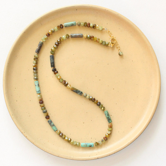 The beaded lana necklace styled on a tan plate to show the adjustable lobster clasp closure