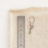 A green kyanite sprout earring next to a ruler for size reference