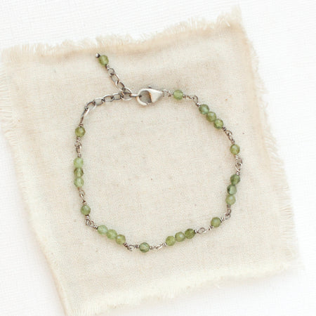 The wrapped green kyanite bracelet styled on tan linen