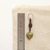 A turquoise leather earring next to a ruler for size reference