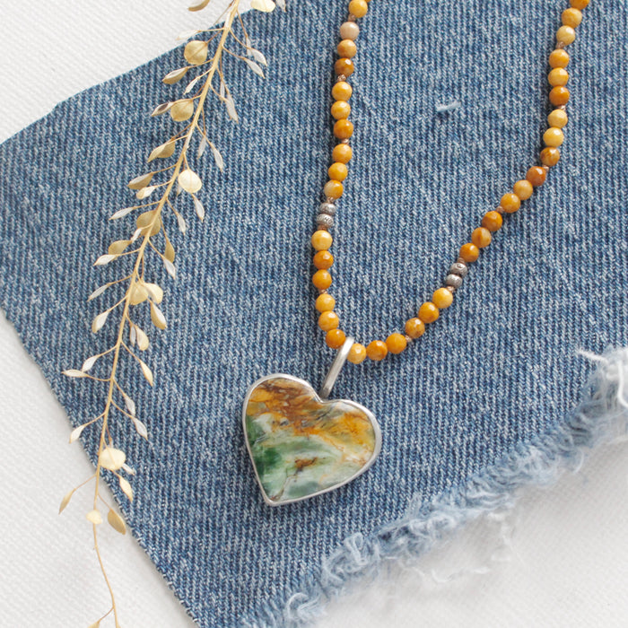 The green variscite and knotted mookaite necklace styled on blue linen with dried grass
