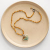 The green variscite and knotted mookiate necklace styled on a tan plate to show the adjustable lobster clasp closure