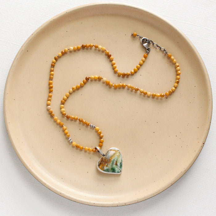 The green variscite and knotted mookiate necklace styled on a tan plate to show the adjustable lobster clasp closure