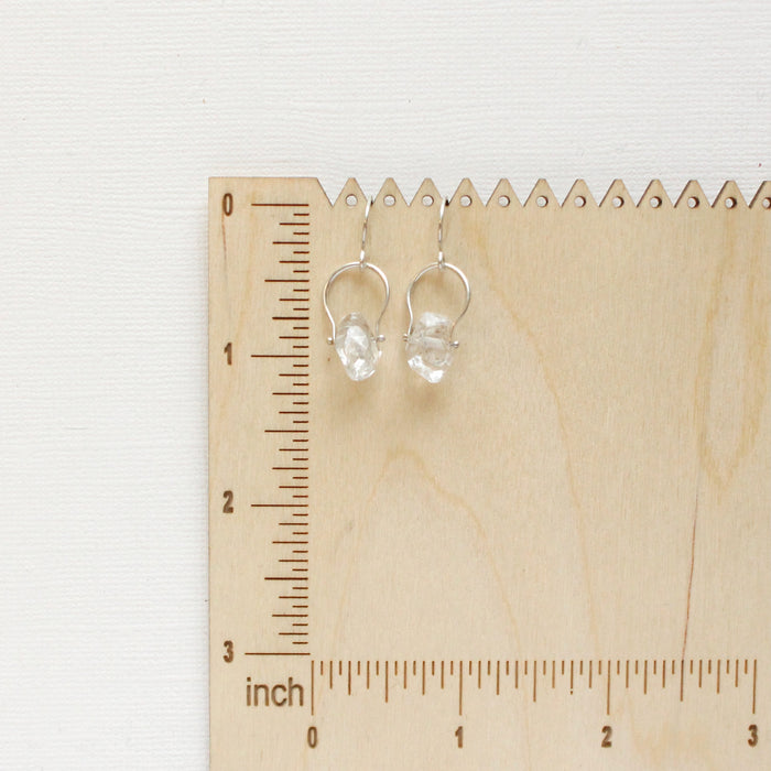 The silver herkimer diamond la cloche earrings on a wooden ruler for size reference