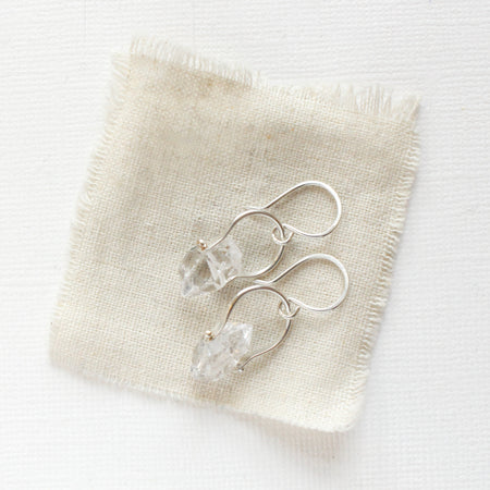 The silver herkimer diamond la cloche earrings styled on tan linen