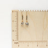 The herkimer diamond mixed metal earrings on a wooden ruler for size reference