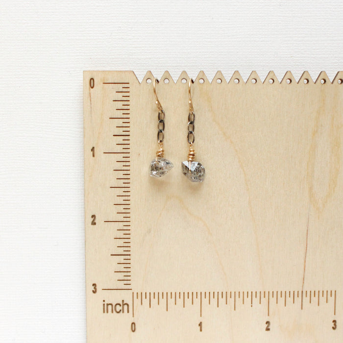 The herkimer diamond mixed metal earrings on a wooden ruler for size reference