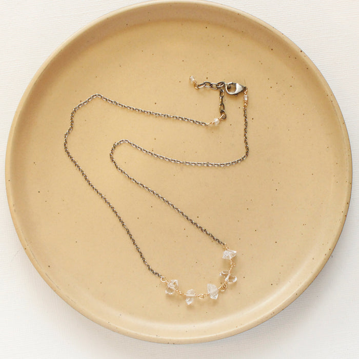 The mixed metal herkimer diamond necklace styled on a tan plate to show the adjustable lobster clasp closure