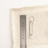 A howlite forged long hoop earrings styled next to a ruler for size reference