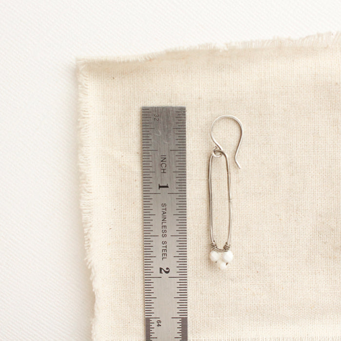 A howlite forged long hoop earrings styled next to a ruler for size reference