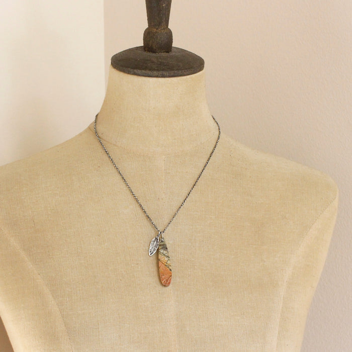 A mannequin wearing the jasper and silver feather necklace