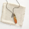 The red creek jasper and silver feather charm necklace styled on tan linen