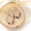 The kaleidoscope hoop earrings styled on wood with linen and dried grass