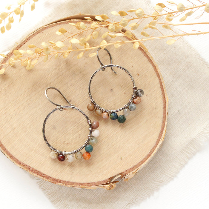 The kaleidoscope hoop earrings styled on wood with linen and dried grass