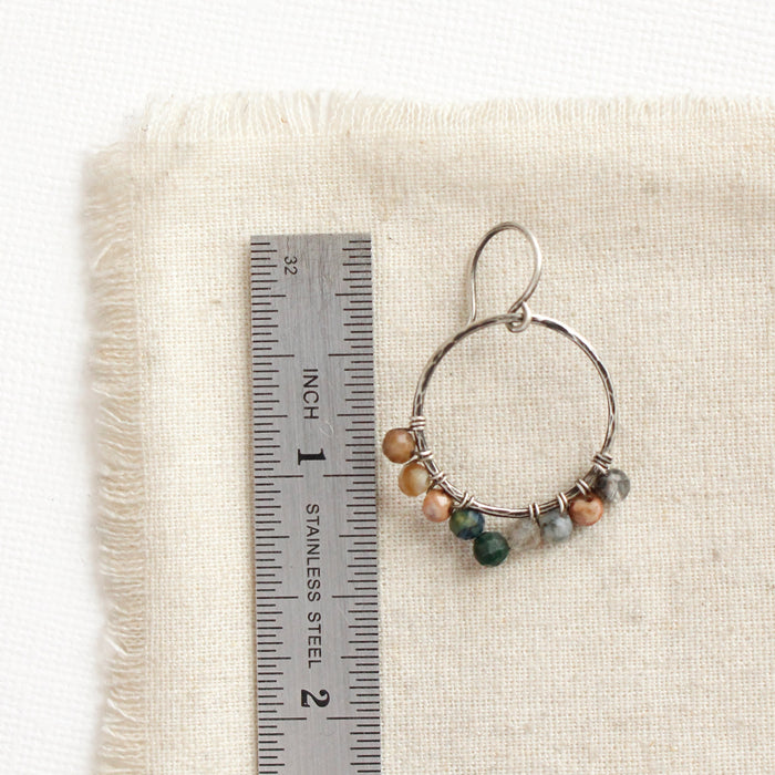 A kaleidoscope hoop earring next to a ruler for size reference