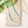 The kingman turquoise and opal necklace styled on a tan rock with green velvet and dried grass