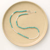 The kingman turquoise and opal necklace styled on a tan plate to show the adjustable lobster clasp closure
