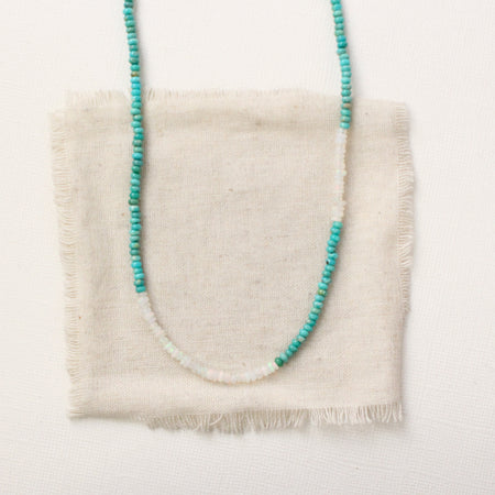 The beaded kingman turquoise and opal necklace styled on tan linen