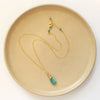 The kingman turquoise and peridot necklace styled on a tan plate to show the adjustable lobster clasp closure