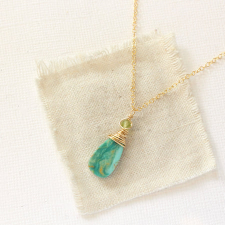 The kingman turquoise and peridot necklace styled on tan linen