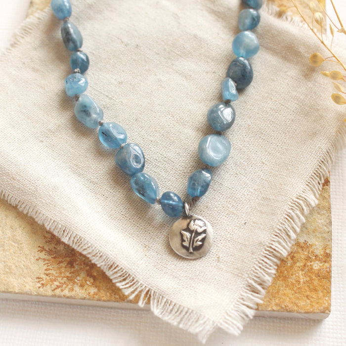 A close up shot of the rose pendant on the knotted aquamarine necklace